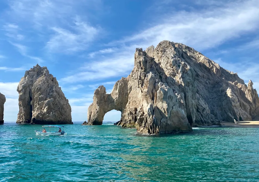 El Arco, the rock arch at the tip of Cabo San Lucas, with a small boat passing through turquoise water